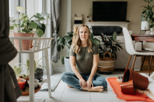 Woman sitting cross legged in room full of house plants Woman sitting cross legged in room full of house plants